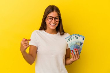 Elinde banknotlar tutan beyaz bir kadın. Sarı arka planda yaşayan biri. Bir tişört fotokopi alanını işaret ediyor.