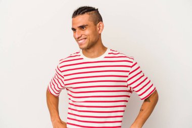 Genç Venezuelalı bir adam beyaz arka planda izole edilmiş, güler ve gözlerini kapatır, rahat ve mutlu hisseder..