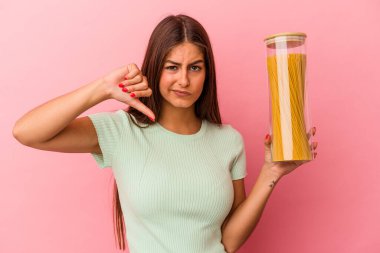 Elinde makarna kavanozu tutan beyaz bir kadın pembe arka planda izole edilmiş, hoş olmayan bir jest gösteriyor. Anlaşmazlık konsepti.