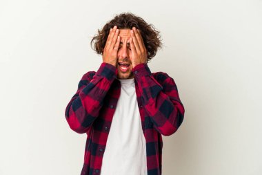 Beyaz arka planda izole edilmiş genç beyaz bir adam yüzünün yarısını palmiye ile örterek eğleniyor..