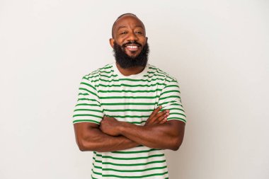 Pembe arka planda sakallı, kendine güvenen, kararlılıkla kollarını kavuşturan Afrikalı Amerikalı bir adam..