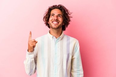 Pembe fırında izole edilmiş genç beyaz adam iki elini de havaya kaldırarak boş bir alan gösterdiğini gösteriyor..