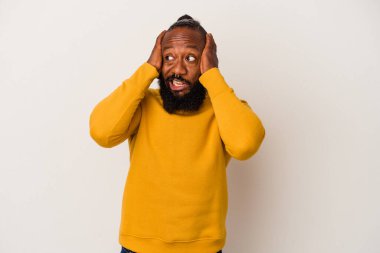 Pembe arka planda sakallı, kulakları elleri kulaklarıyla kapalı, yüksek ses duymamaya çalışan Afrikalı Amerikalı bir adam..