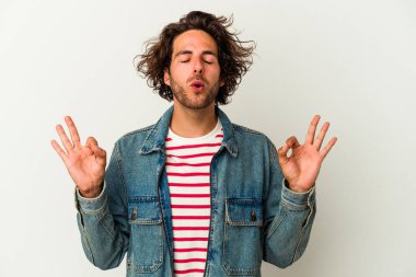 Beyaz arka planda izole edilmiş genç beyaz adam yoğun bir günün ardından rahatlıyor. Yoga yapıyor..