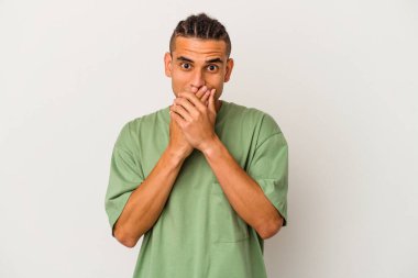 Genç Venezuelalı adam beyaz arka planda izole edilmiş şok olmuş, ağzı ellerle kaplanmış, yeni bir şey keşfetmeye hevesli..