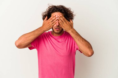 Beyaz arka planda izole edilmiş genç beyaz bir adam elleriyle gözlerini kapatmaktan korkuyor..