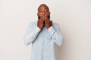 Pembe arka planda sakallı Afrikalı Amerikalı adam elleriyle ağzını kapatırken şok oldu..