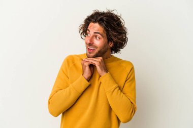 Beyaz arka planda izole edilmiş genç beyaz bir adam şans için dua ediyor, şaşırmış ve ağzını açıp önüne bakıyor..