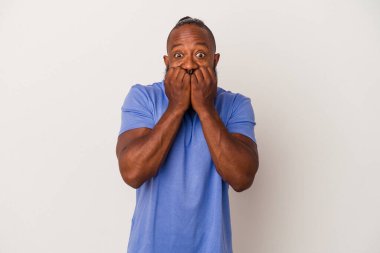 Sakallı Afrikalı Amerikalı bir adam pembe arka planda, tırnak yiyor, gergin ve çok endişeli..
