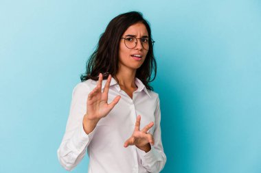 Mavi arka planda izole edilmiş genç beyaz kadın tiksinti belirtisi gösteren birini reddediyor..