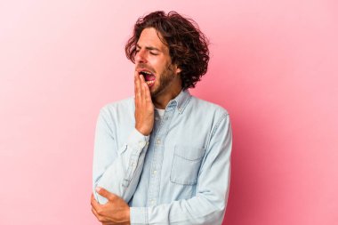 Pembe fırında izole edilmiş genç beyaz adam esniyor. Ağzı eliyle kapatan yorgun bir hareket sergiliyor..