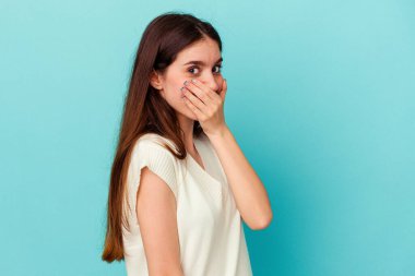 Genç beyaz kadın mavi arka planda izole edilmiş korkmuş ve korkmuş..