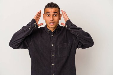 Genç Venezuelalı adam beyaz arka planda izole edilmiş. Şaşırmış ve şok olmuş..