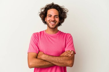 Beyaz arka planda kendini güvende hisseden, kararlılıkla kollarını kavuşturan beyaz tenli genç bir adam..