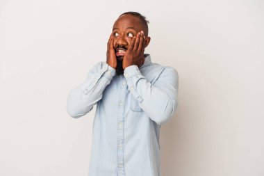 Pembe arka planda sakallı, korkmuş ve korkmuş Afrikalı Amerikalı bir adam..