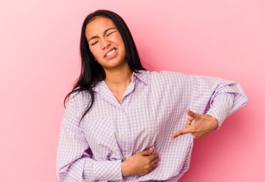 Genç Venezuelalı kadın pembe arka planda izole edilmiş karaciğer ağrısı, mide ağrısı var..