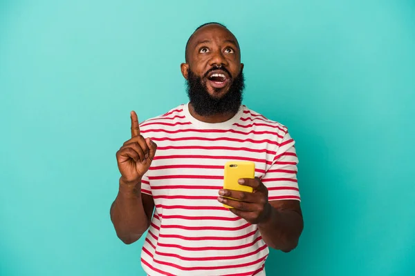 非洲裔美国人手持一部蓝色背景的手机 上边有开口 — 图库照片