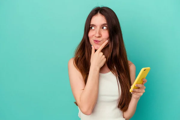 Junge Kaukasische Frau Hält Ein Handy Isoliert Auf Blauem Hintergrund — Stockfoto