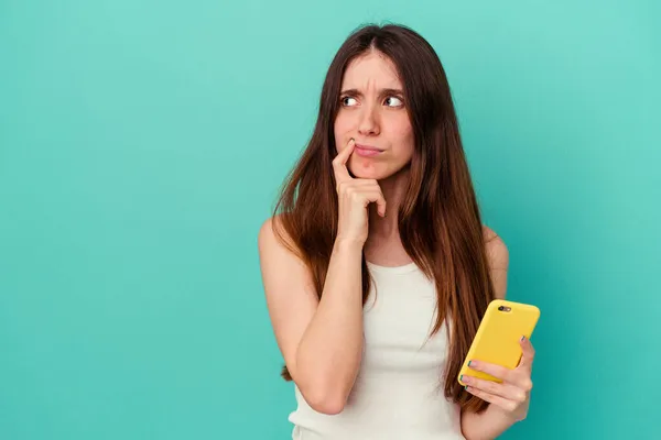 Jonge Blanke Vrouw Met Een Mobiele Telefoon Geïsoleerd Blauwe Achtergrond — Stockfoto