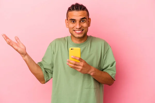 Młody Wenezuelczyk Trzymający Telefon Komórkowy Odizolowany Różowym Tle Otrzymuje Miłą — Zdjęcie stockowe