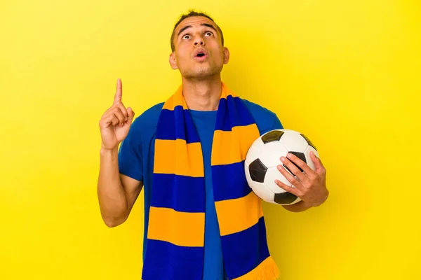 若いですVenezuelan男見ますサッカー孤立上の黄色の背景ポインティングアップサイドとともにオープン口 — ストック写真