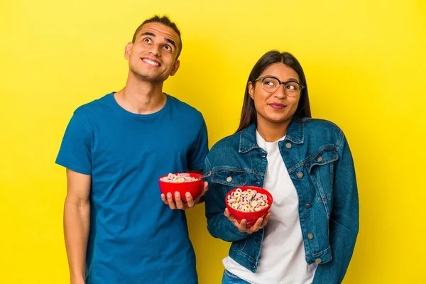 Jovem Casal Latino Segurando Uma Tigela Cereais Isolado Fundo Amarelo — Fotografia de Stock