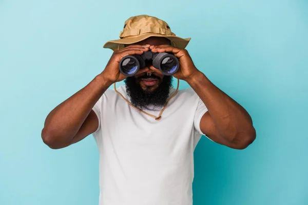 African american man holding binoculars isolated on blue background