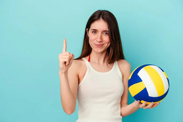 Молода Біла Жінка Грає Волейбол Ізольовано Синьому Фоні Показуючи Номер — стокове фото