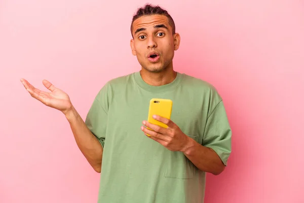 Młody Wenezuelczyk Trzyma Telefon Komórkowy Odizolowany Różowym Tle Zaskoczony Zszokowany — Zdjęcie stockowe