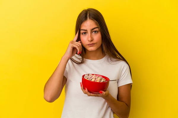 Mulher Branca Jovem Segurando Cereais Isolados Fundo Amarelo Apontando Templo — Fotografia de Stock