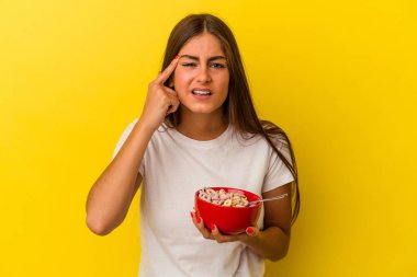 Sarı arka planda mısır gevreği tutan beyaz bir kadın işaret parmağıyla yaptığı hayal kırıklığını gösteriyor..