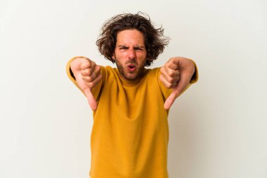 Beyaz arka planda izole edilmiş genç beyaz bir adam baş parmağını aşağı gösteriyor ve hoşlanmadığını ifade ediyor..