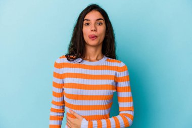 Mavi arka planda izole edilmiş genç beyaz kadın karnına dokunuyor, nazikçe gülümsüyor, yemek yiyor ve tatmin oluyor..