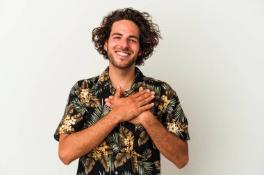 Beyaz arka planda izole edilmiş beyaz tenli genç bir adam, dostane bir ifadeye sahip, avuçlarını göğsüne bastırıyor. Aşk konsepti.