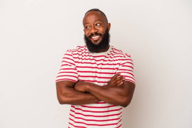 Pembe arka planda sakallı Afrikalı Amerikalı adam kollarını kavuşturup gülümsüyor..