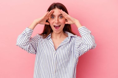 Pembe arka planda izole genç beyaz kadın zaferi ya da başarıyı kutluyor, şaşırıyor ve şok oluyor..