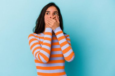 Kafkasyalı genç bir kadın mavi arka planda izole edilmiş düşünceli bir şekilde ağzıyla ağzını kapatan bir fotokopi odasına bakıyor..