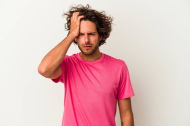 Beyaz arka planda izole edilmiş genç beyaz bir adam yorgun ve uykulu bir şekilde elini başının üstünde tutuyor..