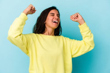 Genç beyaz kadın mavi arka planda izole edilmiş zafer sonrası yumruğunu kaldırıyor, kazanan konsept..