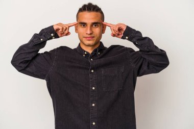 Venezuelalı genç bir adam beyaz arka planda izole edilmiş vazifesine odaklanmış, işaret parmaklarını işaret ediyor..