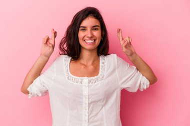 Pembe arka planda izole edilmiş beyaz bir kadın şans getirsin diye dua ediyor.