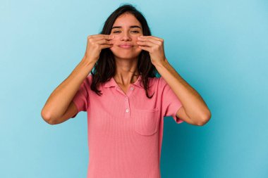 Kafkasyalı genç bir kadın mavi arka planda izole edilmiş. İki seçenek arasında şüpheli..