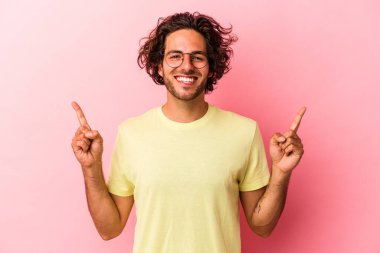 Pembe fırında izole edilmiş genç beyaz adam iki elini de havaya kaldırarak boş bir alan gösterdiğini gösteriyor..