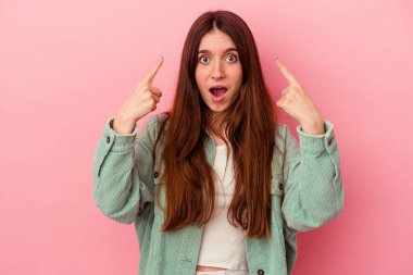 Pembe arka planda izole edilmiş beyaz bir kadın ağzı açık bir şekilde üst tarafı işaret ediyor..