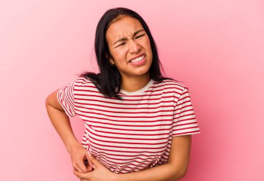 Genç Venezuelalı kadın pembe arka planda izole edilmiş karaciğer ağrısı, mide ağrısı var..