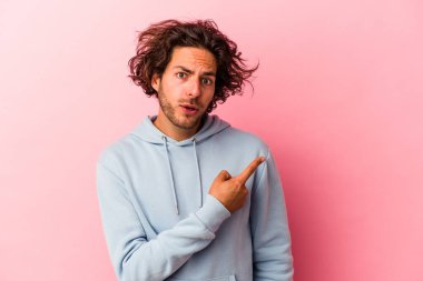 Pembe fırında izole edilmiş genç beyaz adam yan tarafı işaret ediyor.