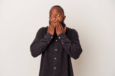 Sakallı Afrikalı Amerikalı bir adam pembe arka planda izole edilmiş. Düşünceli bir şekilde bir fotokopi odasına bakıyor. Ağzını eliyle kapatıyor..