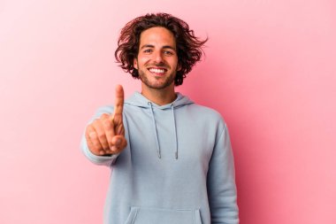 Pembe fırında izole edilmiş genç beyaz bir adam bir numarayı parmağıyla gösteriyor..