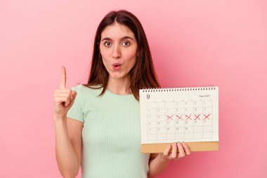 Pembe arka planda takvime izole edilmiş beyaz bir kadın. Harika bir fikri var, yaratıcılık kavramı..