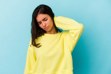 Mavi arka planda izole edilmiş genç beyaz kadın sabit yaşam tarzından dolayı boyun ağrısından muzdarip..
